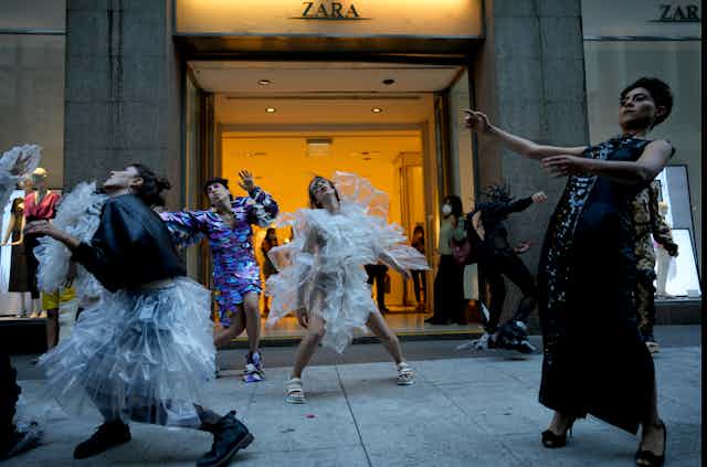 People dance in front of a store front.