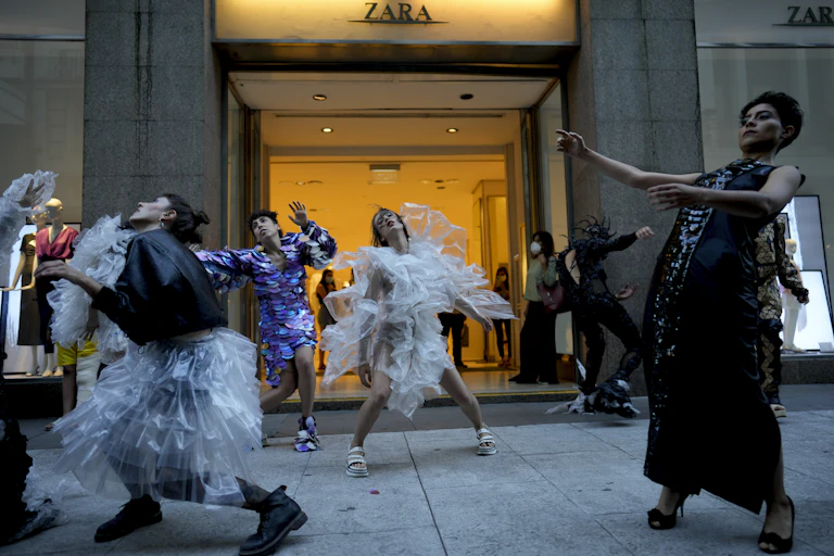People dance in front of a store front.