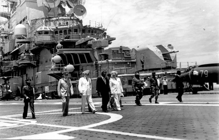 black and white photo showing men on the deck of an aircraft carrier