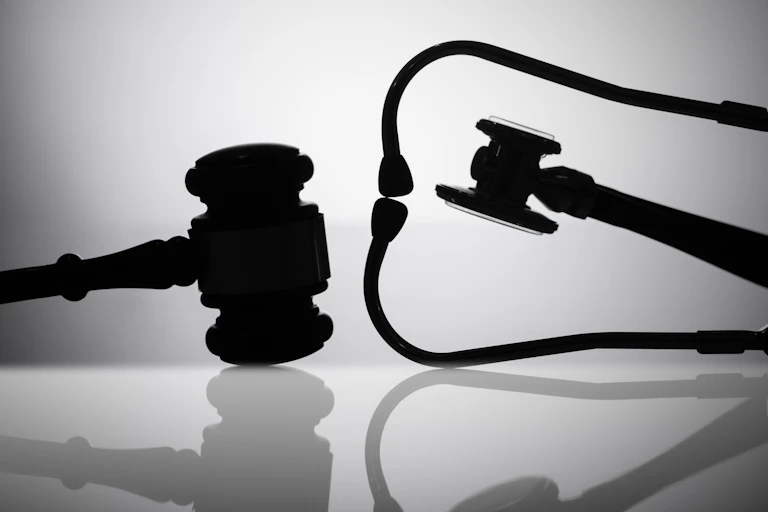 Silhouettes of a judge's gavel and a stethoscope.