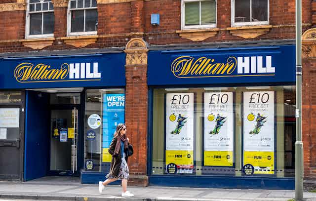 A woman walks past UK betting shop William Hill