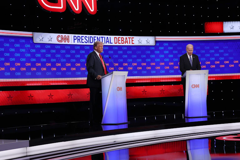 Two white men dressed in business suits stand behind podiums.