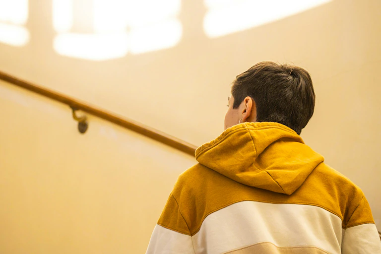 A young man in a hoodie jumper walks up a staircase.