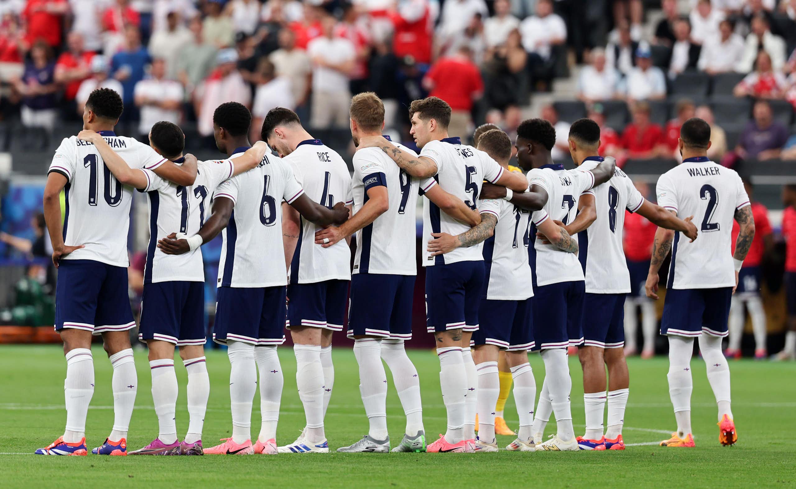 The England team seen from behind lined up with arms linked before a match at EEuro 2024.