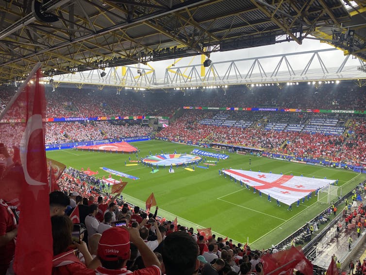 A photo taken from the stands of as players take to a pitch displaying huge Turkey and Georgia flags.