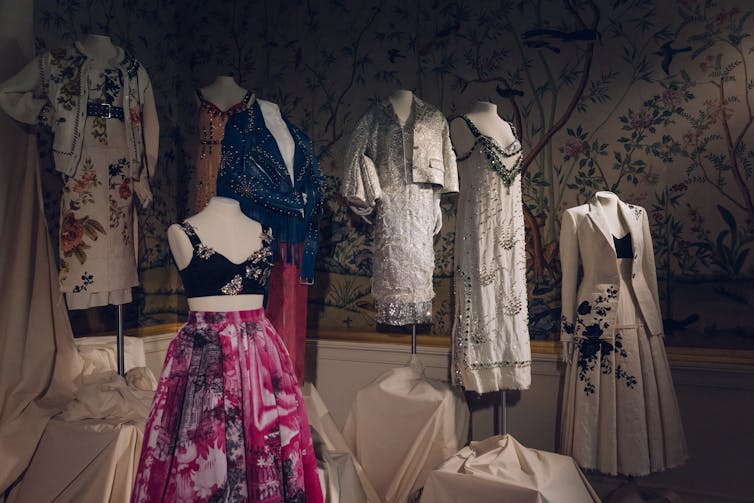 A selection of ladies' fashion outfits on display against a floral wallpaper background.