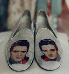 A pair of grey velvet shoes with Elvis on them.