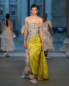 A model wearing an off the shoulder dress with a yellow satin skirt.