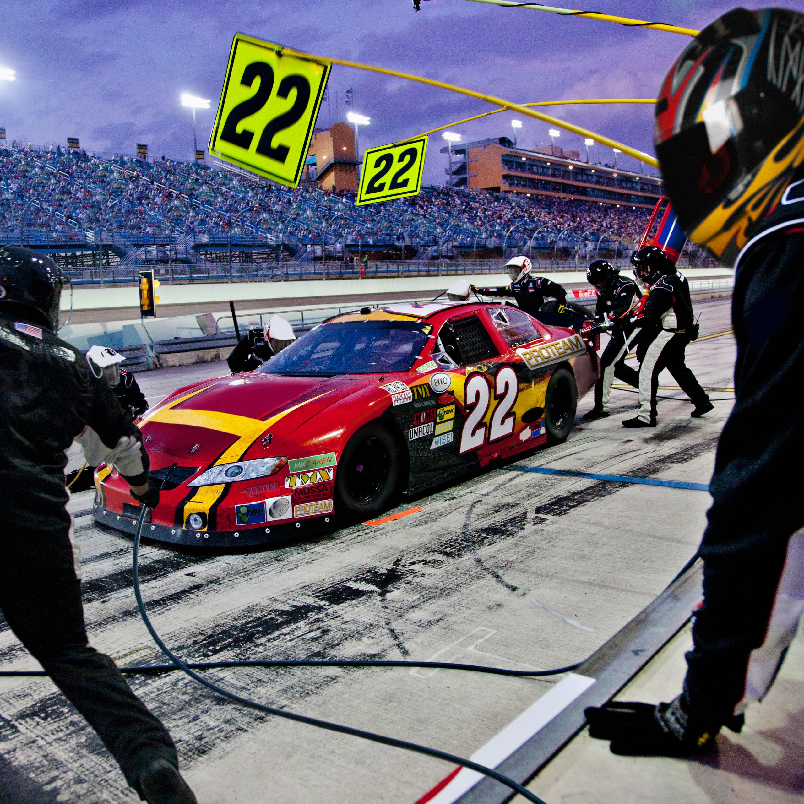 A pit crew works on a car at a racetrack.
