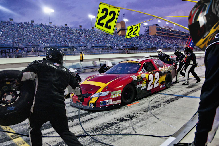 A pit crew works on a car at a racetrack.