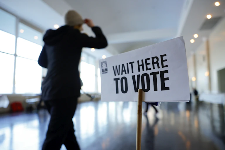 A person approaches a wait here to vote sign.