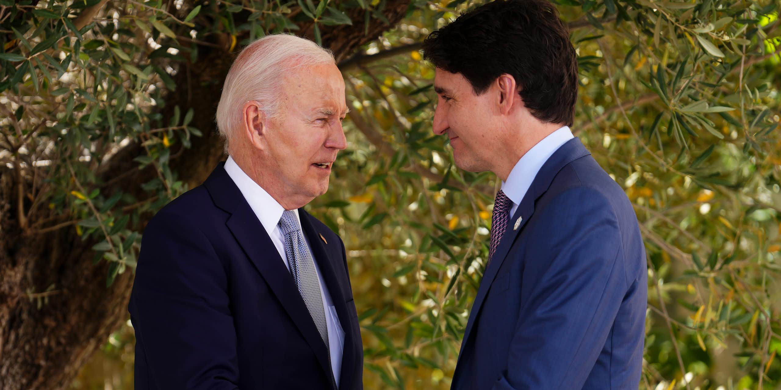 Trudeau on the right grasps Biden's hand.