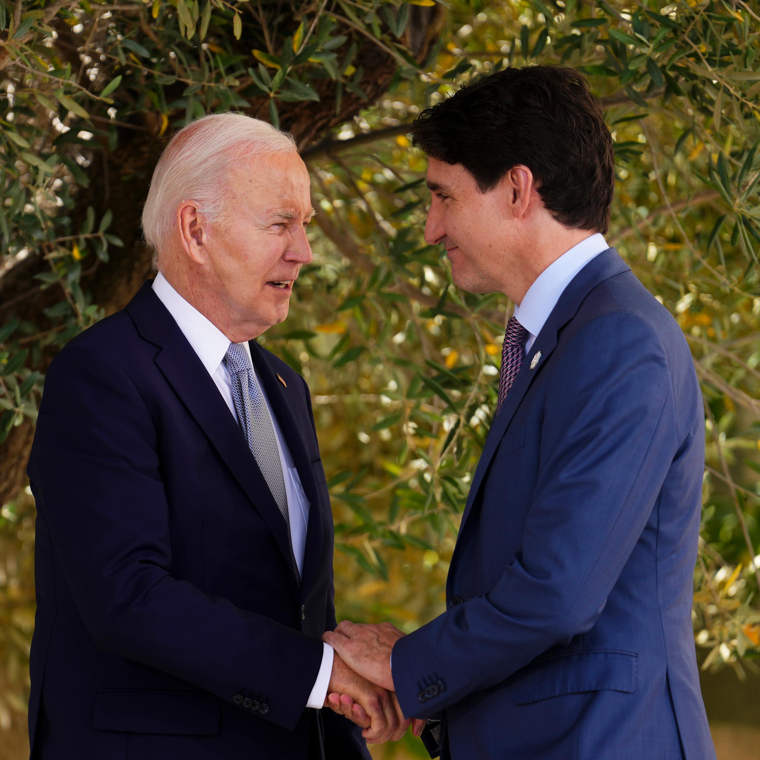 Trudeau on the right grasps Biden's hand.