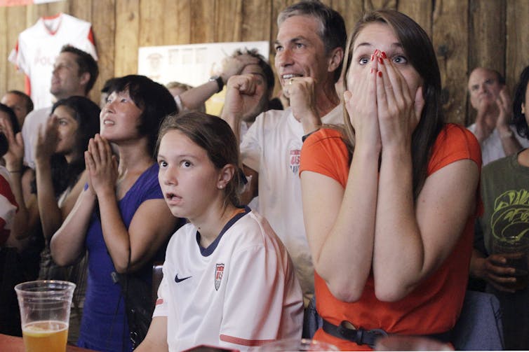 A handful of people standing inside put their hands up to their faces in suspense.