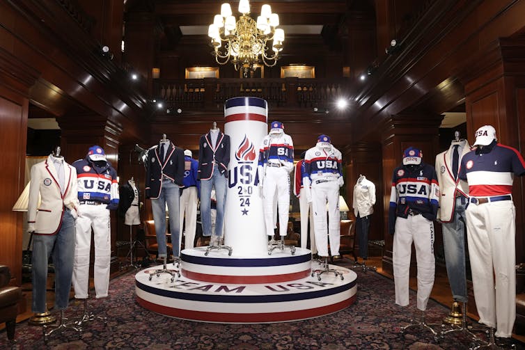 A formal showroom with mannequins in red, white and blue sports outfits.