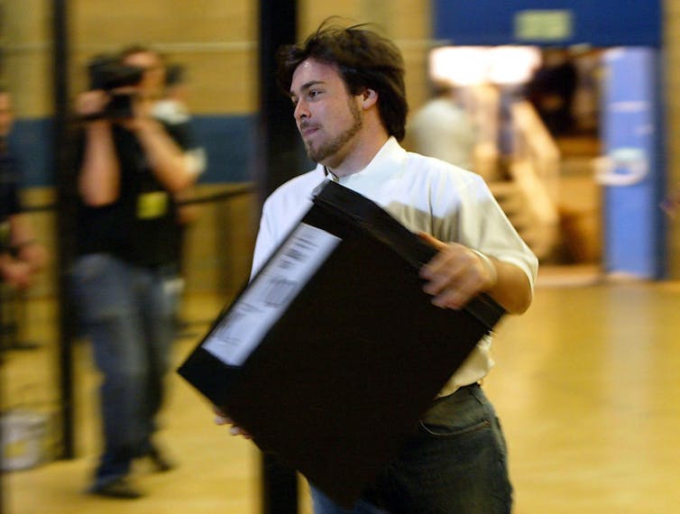Um homem correndo com uma urna eleitoral.