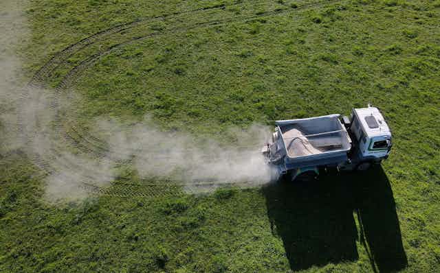 An aerial view of a truck spreading fertiliser on a dairy farm