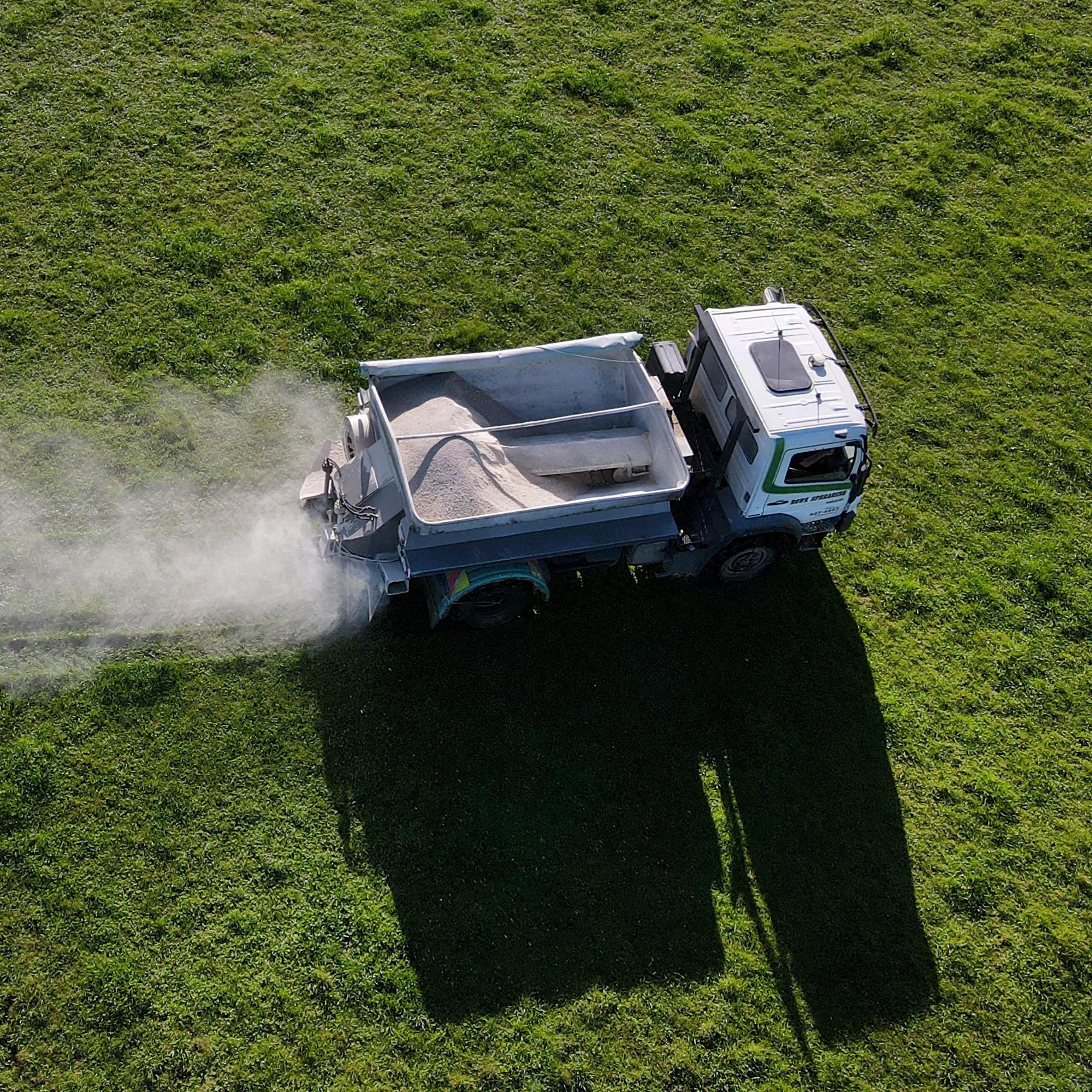 An aerial view of a truck spreading fertiliser on a dairy farm