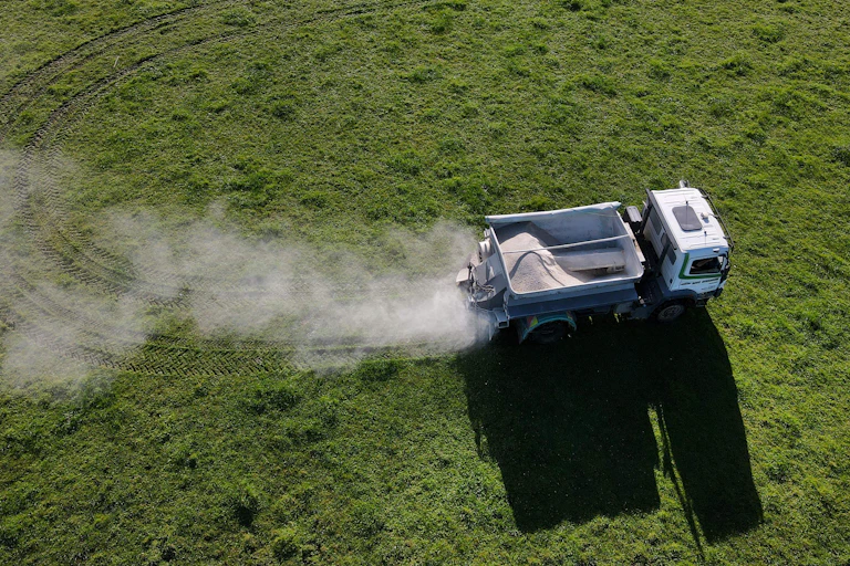 An aerial view of a truck spreading fertiliser on a dairy farm