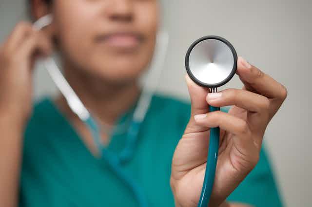 A female healthcare professional taking a reading using a stethoscope 