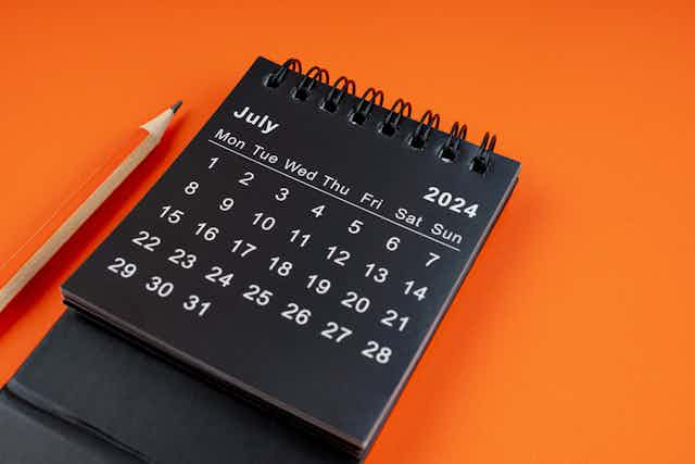 Desk calendar seen on orange background with orange pencil 