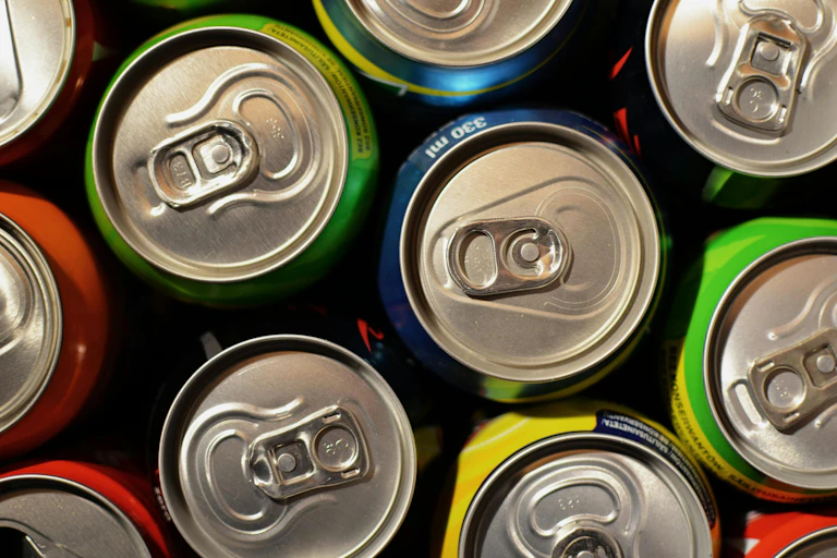 A bunch of drink soda cans are displayed from the top down, in a birds eye view.