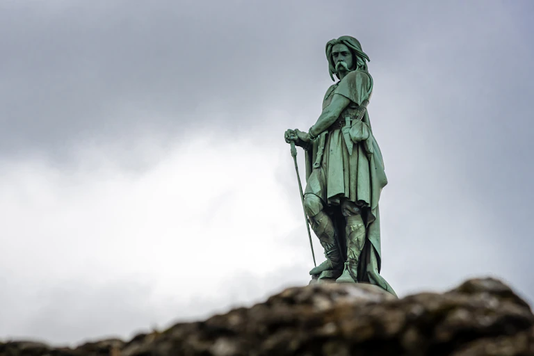 A statue of Vercingetorix, Gallic historical warrior, stands against the skyline.