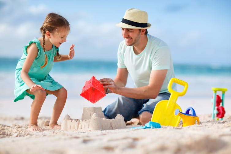 Young girl and man making sandcastle on a beach