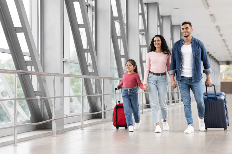 Family pulling suitcases at an airport