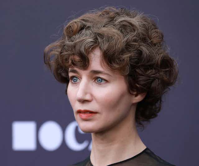A woman with short, dark curly hair.