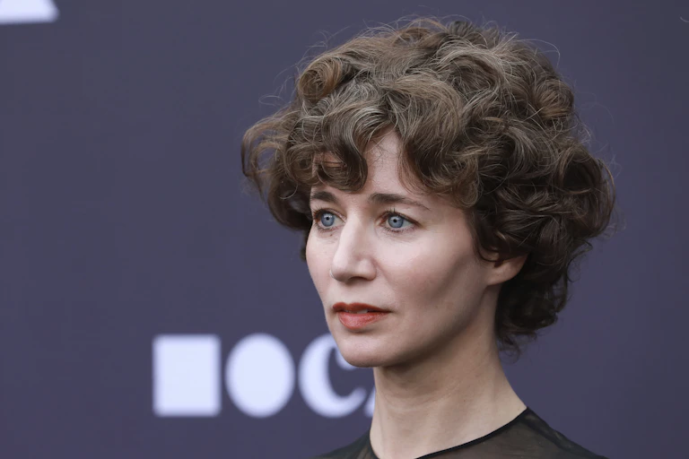 A woman with short, dark curly hair.