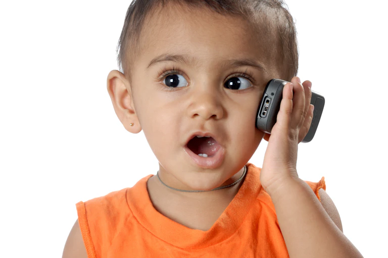 Portrait of one year cute little baby girl talking on mobile phone white background