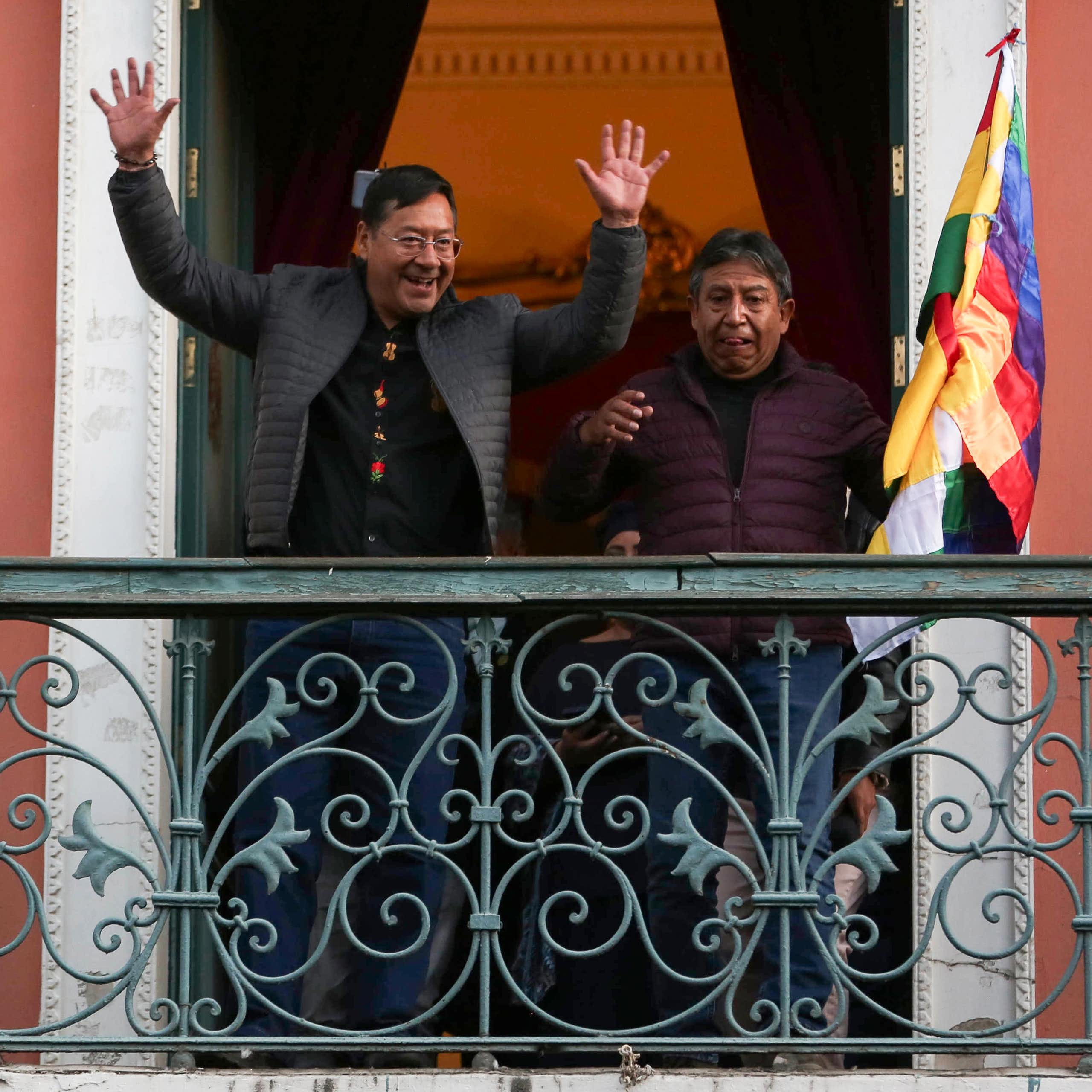Luis Arce and his vice president standing on a balcony greeting supporters.