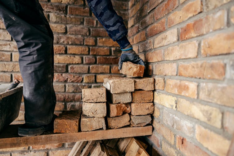 A bricklayer piling bricks.