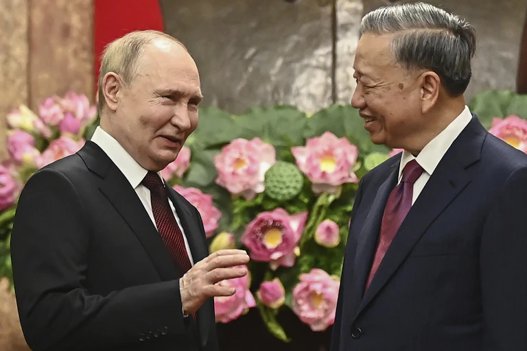 Two men in suits smile which talking