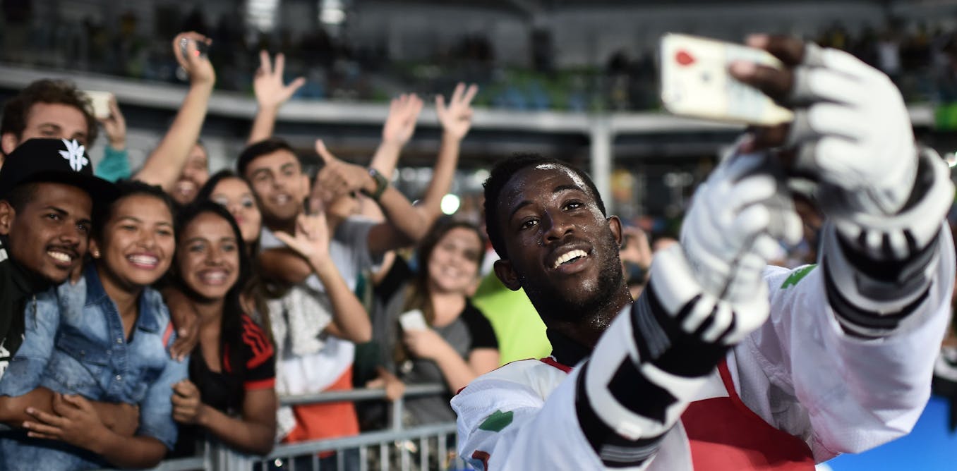 Olympics 2024: what new social media guidelines mean for athletes and their sponsors 'a man with his arms raised in front of a crowd'