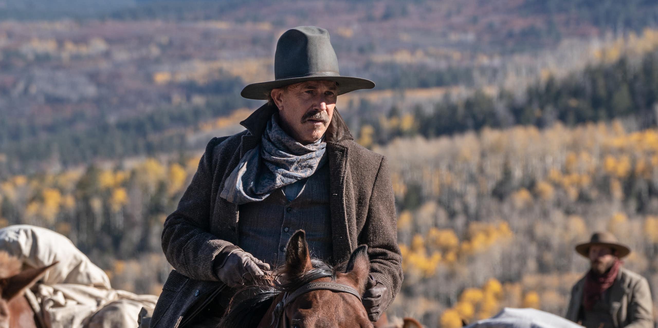 Kevin Costner in western clothes riding a horse