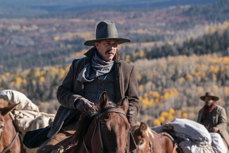 Kevin Costner in western clothes riding a horse