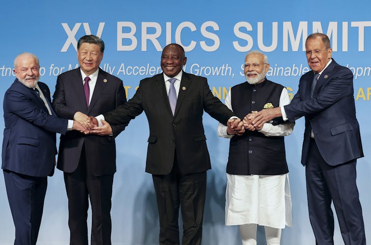 people stand in a row holding hands while posing for a photo.