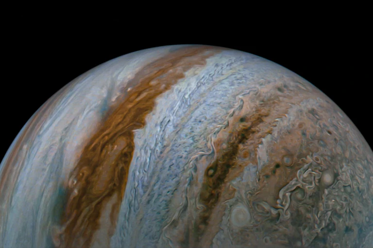 An image of Jupiter shows cloud tops and colorful blue and brown belts covering the planet.