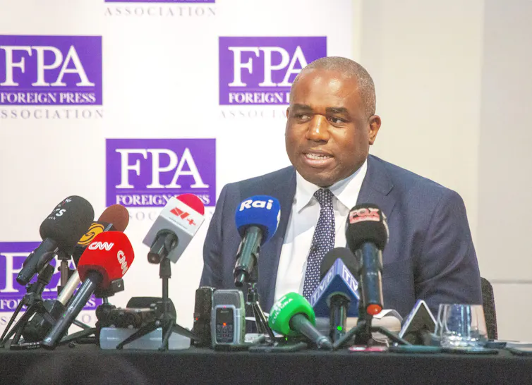 David Lammy talking into multiple microphones.