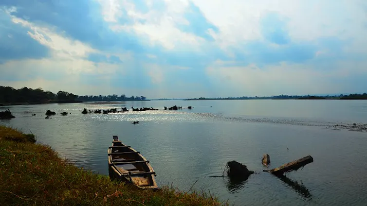 A view of a wide river with a small hand-made boat on the shore.