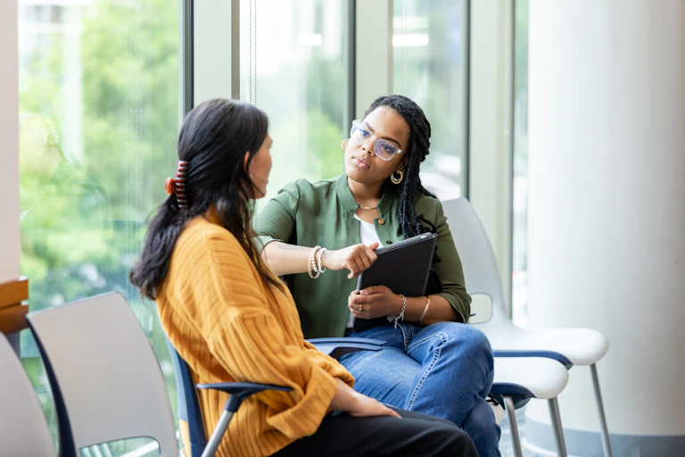 An empathetic-looking female counselor tilts her head and listens as a vulnerable patient shares about a difficult situation.
