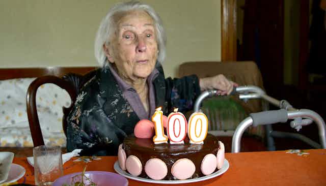 Uma mulher com um bolo comemorando a chegada aos 100 anos