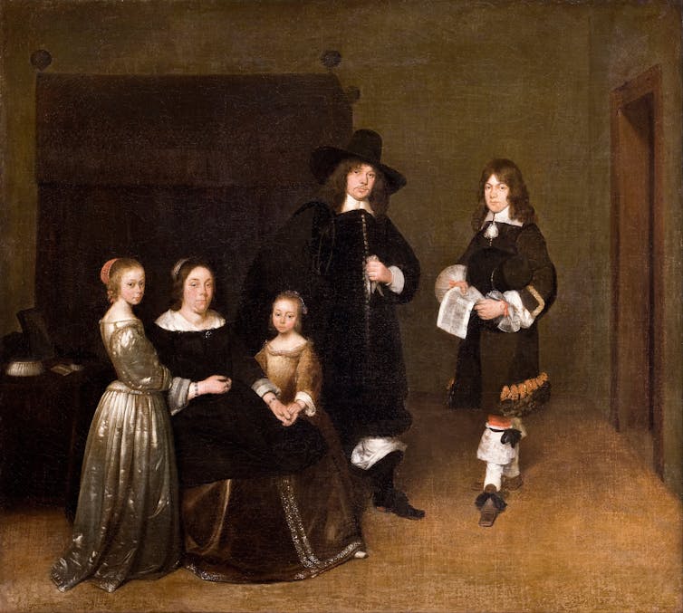 A family in front of a bed.