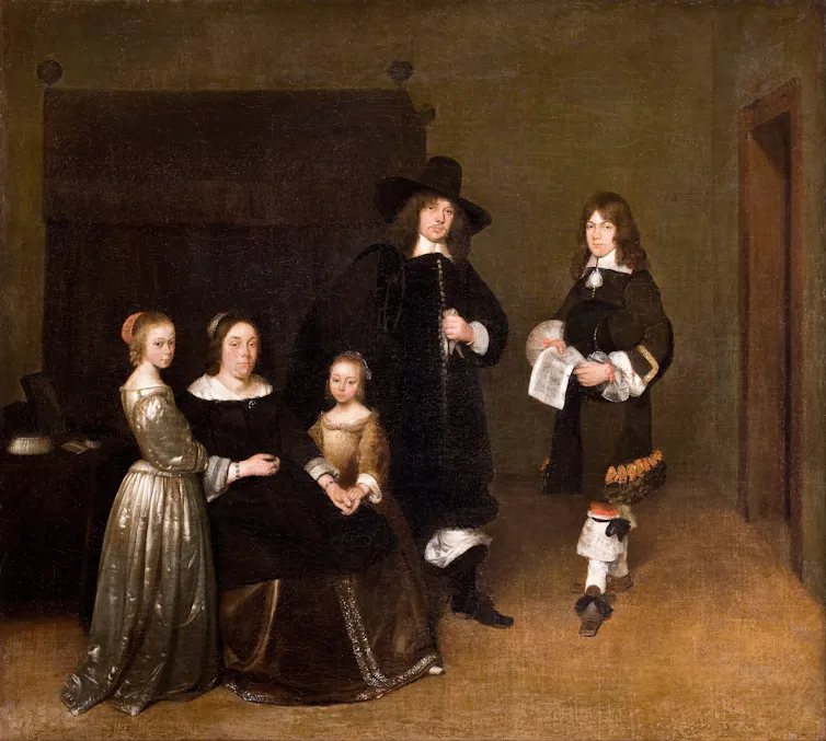 A family in front of a bed.