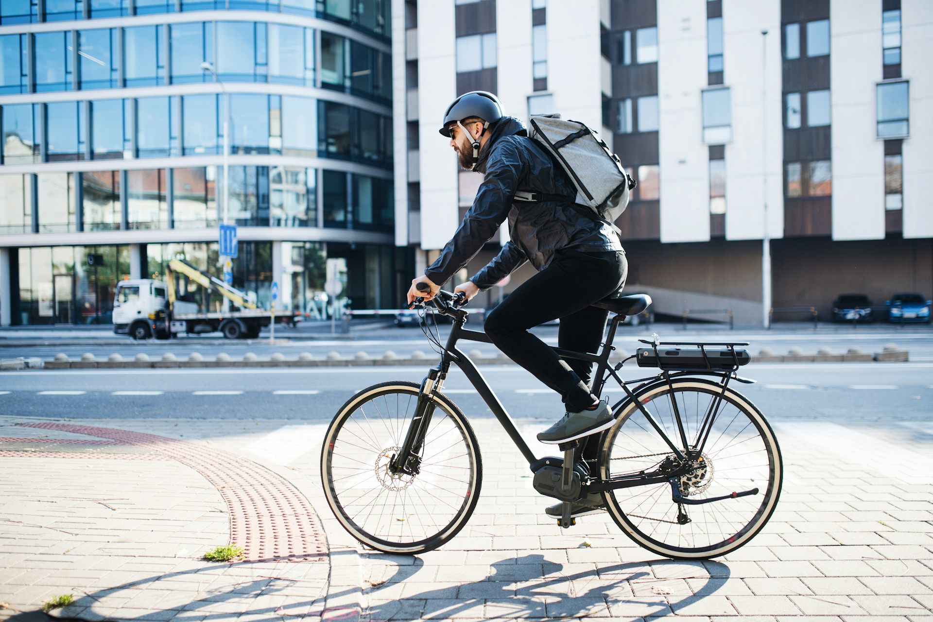 man with backpack rides e-bike