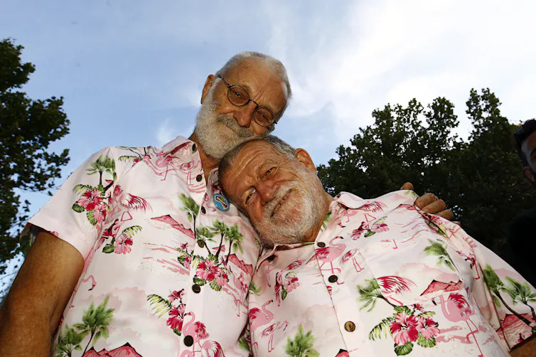 Two men in matching pink Hawaiin shirts.