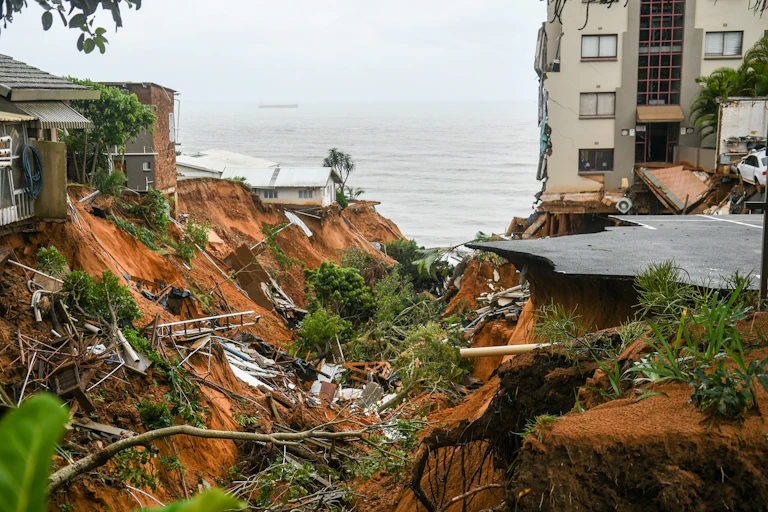 The sea in the background and some collapsed buildings nearby with a huge ravine torn through the middle