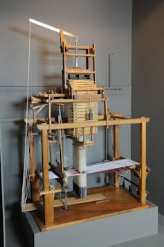 Un métier à tisser dans un musée. Au centre, on aperçoit les cartes perforées qui passent à travers la machine